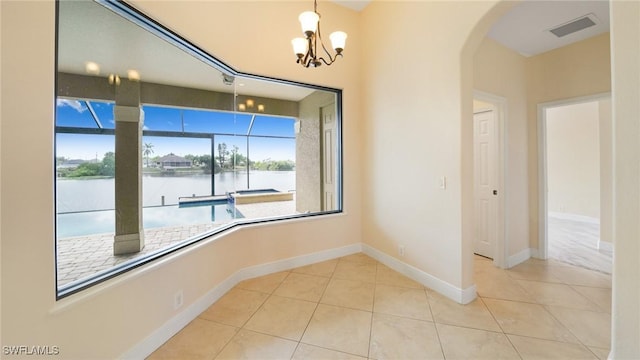 unfurnished dining area featuring a chandelier, a water view, and light tile patterned flooring