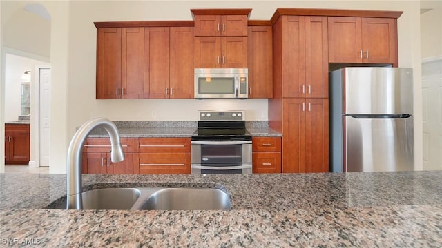 kitchen with appliances with stainless steel finishes, sink, and light stone counters