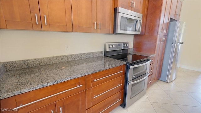 kitchen featuring light tile patterned floors, stainless steel appliances, and light stone countertops