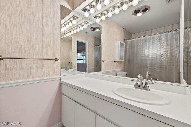 bathroom with toilet, vanity, and a shower with shower curtain