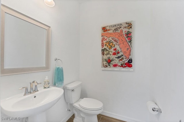 bathroom with a sink, toilet, and baseboards