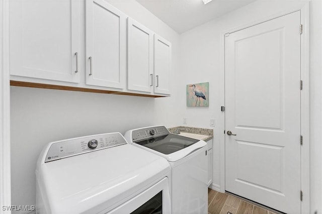 laundry room with a sink, separate washer and dryer, light wood-style flooring, and cabinet space