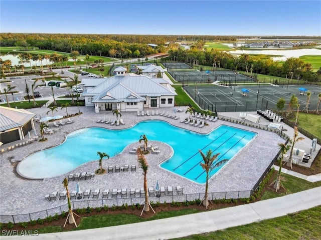 community pool with a water view, fence, and a patio