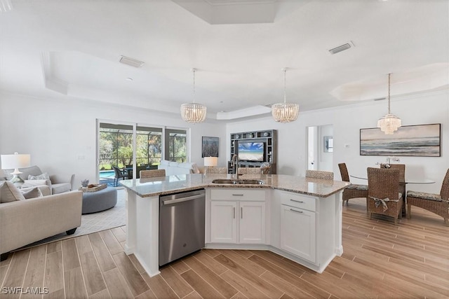 kitchen featuring white cabinetry, open floor plan, stainless steel dishwasher, and decorative light fixtures