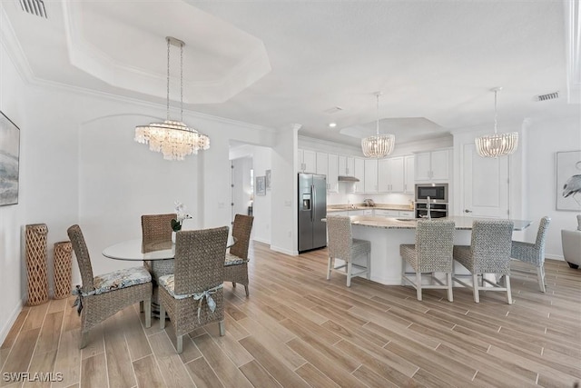 dining room featuring wood tiled floor, a raised ceiling, visible vents, and a notable chandelier