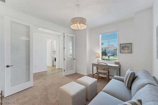 living area with a chandelier, french doors, light colored carpet, and baseboards