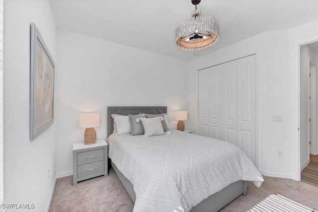 bedroom with a closet, light colored carpet, and baseboards