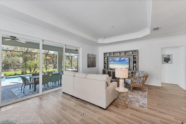 living room featuring visible vents, a sunroom, wood tiled floor, a tray ceiling, and crown molding