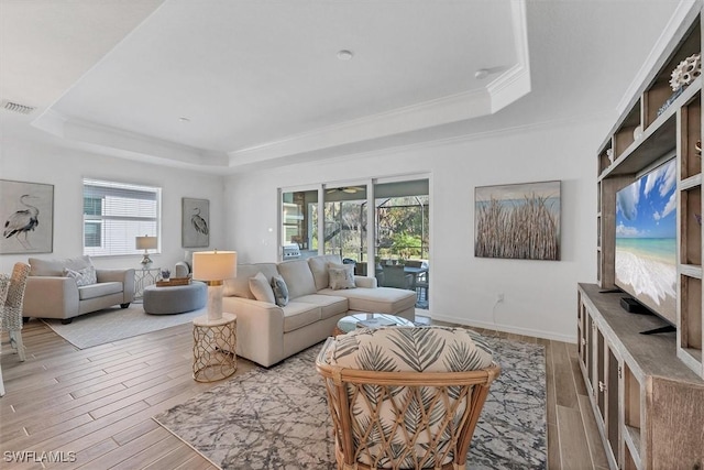 living area featuring light wood-style floors, a tray ceiling, and visible vents