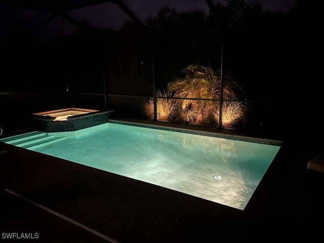 pool at night featuring an in ground hot tub