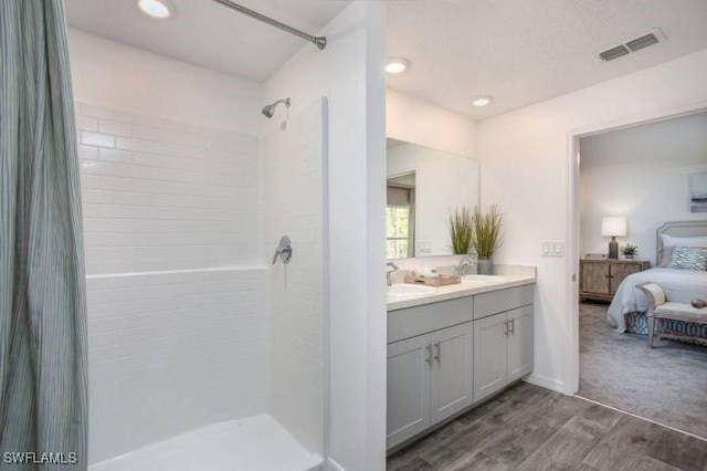 bathroom featuring vanity, a tile shower, and wood-type flooring