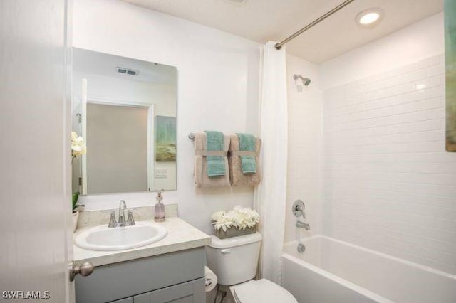 full bathroom featuring tiled shower / bath combo, vanity, and toilet