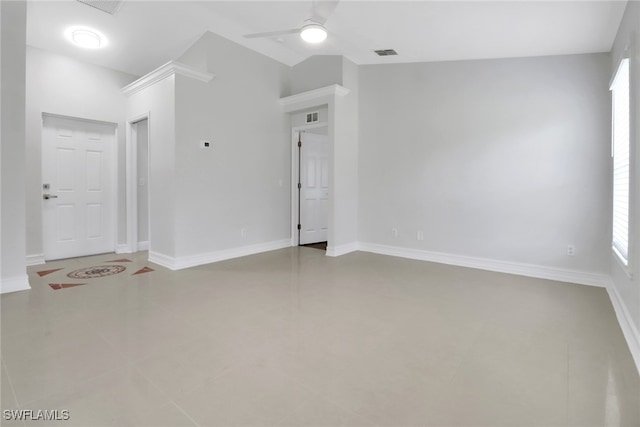 tiled empty room featuring baseboards, visible vents, vaulted ceiling, and a ceiling fan