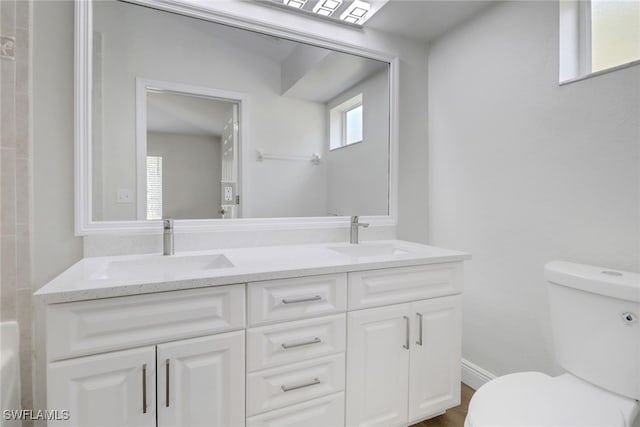 bathroom with double vanity, toilet, and a sink