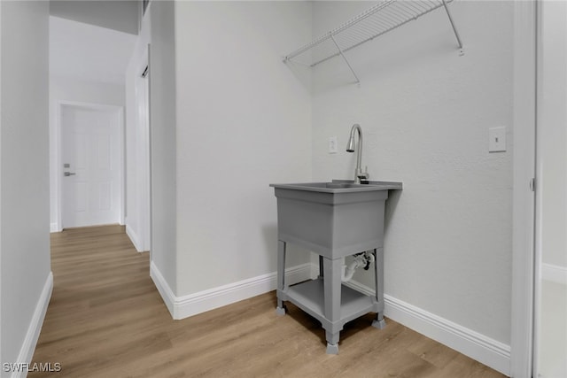 laundry area featuring light wood-style flooring and baseboards