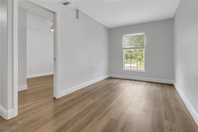 spare room with wood finished floors, visible vents, and baseboards