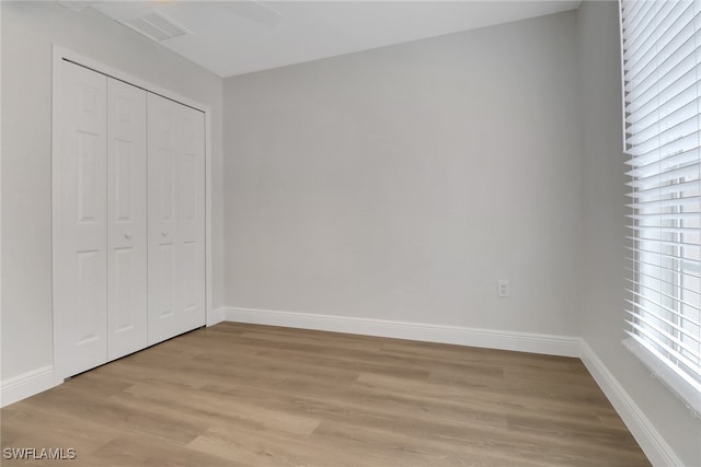 unfurnished bedroom featuring light wood-style floors, a closet, visible vents, and baseboards