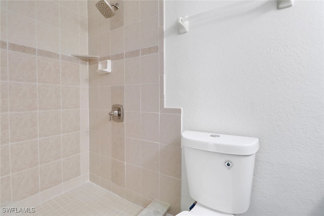 full bathroom with a textured wall, a tile shower, and toilet