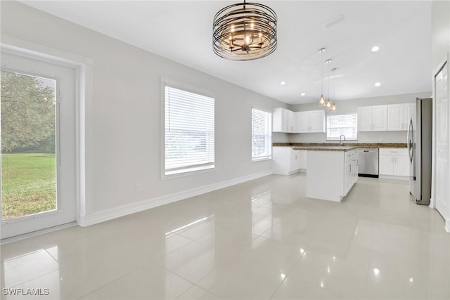 kitchen featuring appliances with stainless steel finishes, open floor plan, decorative light fixtures, a center island, and white cabinetry