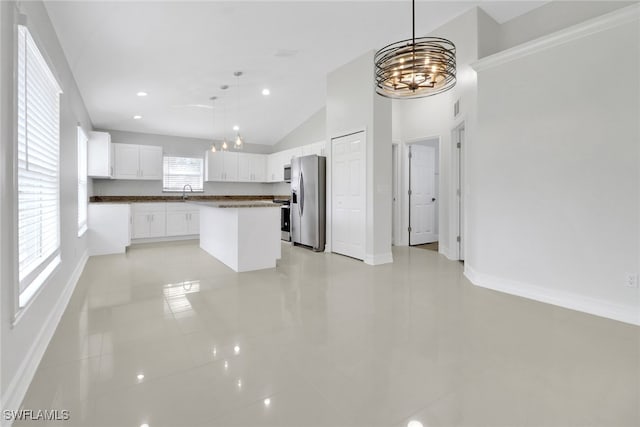 kitchen with hanging light fixtures, appliances with stainless steel finishes, open floor plan, white cabinetry, and a kitchen island