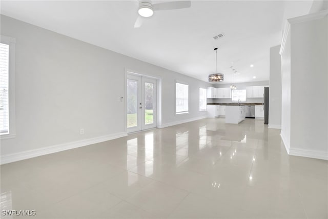 unfurnished living room with plenty of natural light, visible vents, baseboards, and french doors