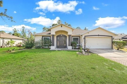 view of front of property with concrete driveway, an attached garage, a front yard, and stucco siding