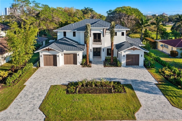 modern inspired farmhouse featuring decorative driveway, a standing seam roof, metal roof, and a garage