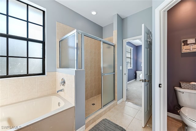 bathroom with tile patterned flooring, toilet, baseboards, a bath, and a stall shower