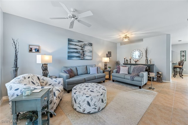 living area featuring light tile patterned floors, ceiling fan, and baseboards