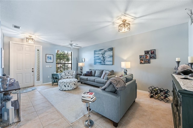 living area with light tile patterned flooring, ceiling fan, visible vents, and baseboards