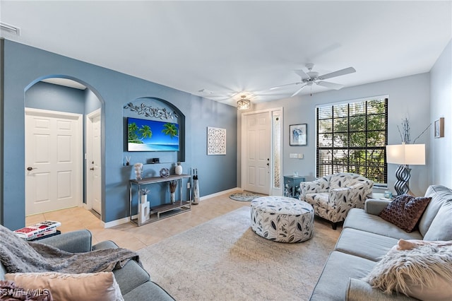 living room featuring baseboards, visible vents, arched walkways, ceiling fan, and light tile patterned flooring