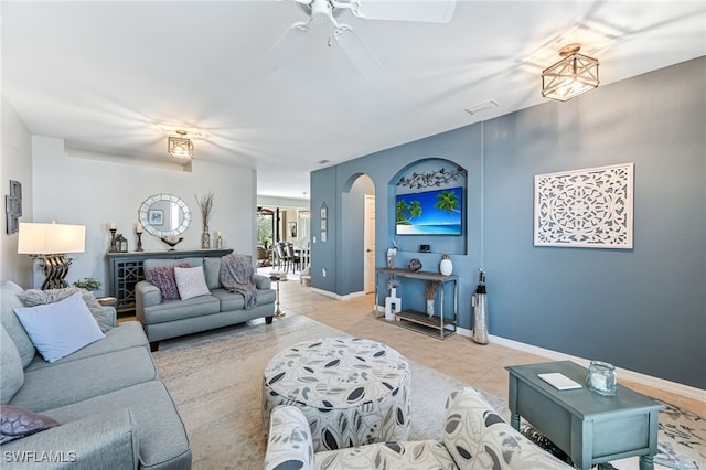 tiled living room with arched walkways, ceiling fan, and baseboards