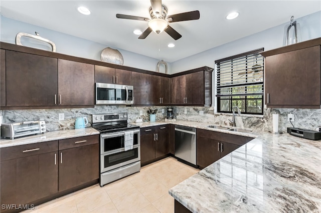 kitchen with light stone counters, a toaster, stainless steel appliances, a sink, and dark brown cabinets