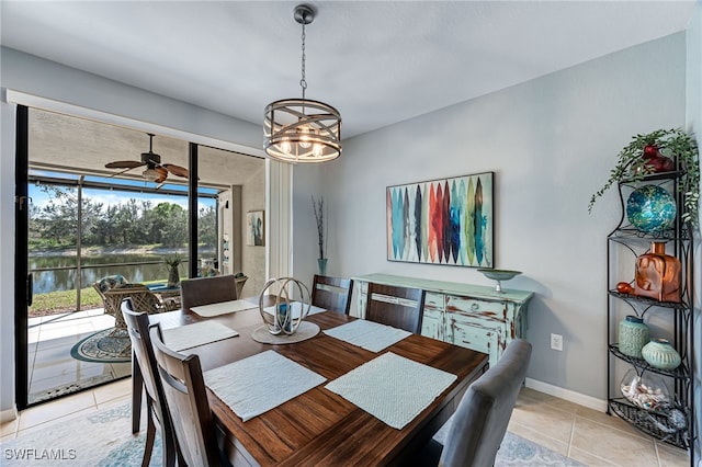 dining space with a water view, ceiling fan, baseboards, and light tile patterned floors