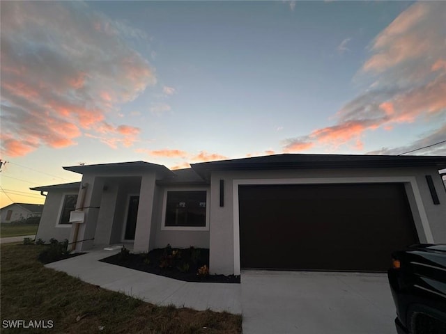 view of front of property with driveway, an attached garage, and stucco siding