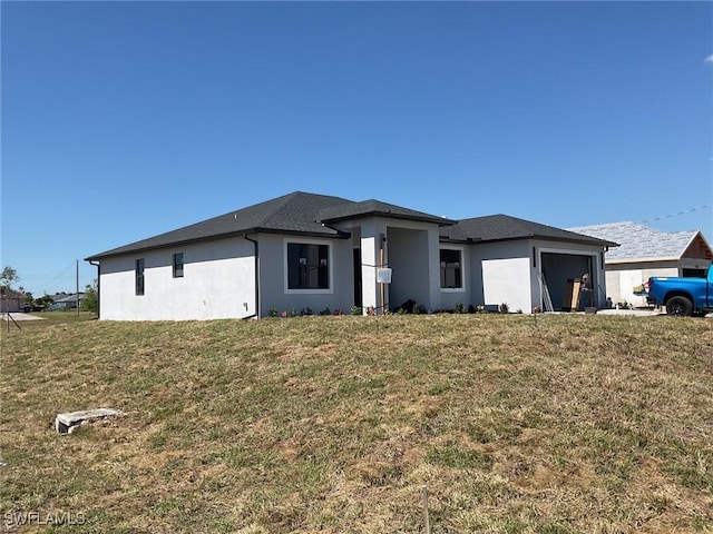 view of front of house featuring a front lawn, an attached garage, and stucco siding