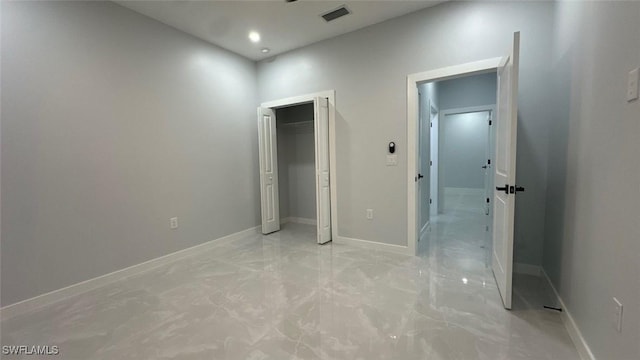 unfurnished bedroom with marble finish floor, a closet, visible vents, and baseboards