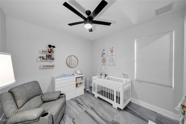 bedroom with ceiling fan and a nursery area