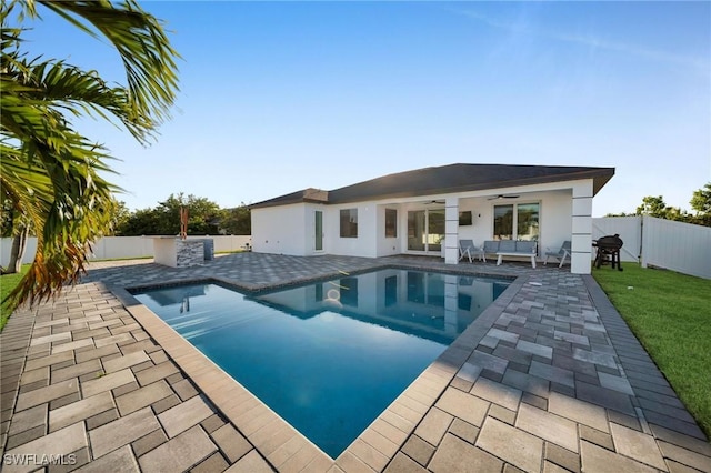 view of swimming pool with a patio, an outdoor kitchen, and ceiling fan