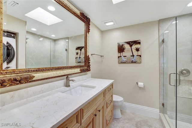 bathroom with vanity, a skylight, an enclosed shower, washer / dryer, and toilet