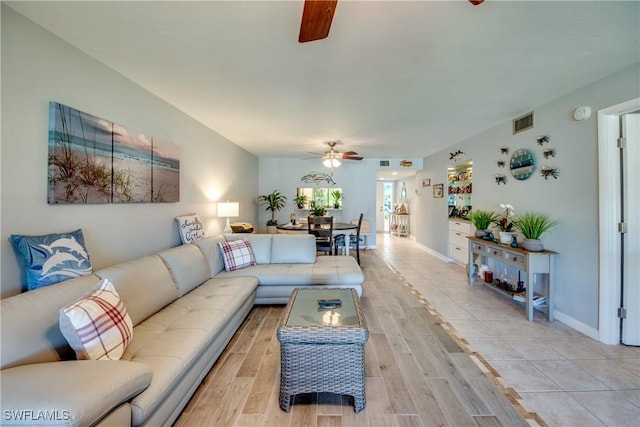 living room with visible vents, ceiling fan, light wood-style flooring, and baseboards