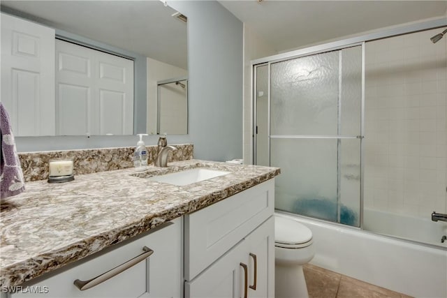 full bathroom featuring combined bath / shower with glass door, vanity, toilet, and tile patterned floors