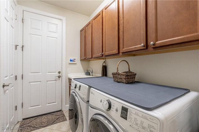 washroom featuring light tile patterned floors, independent washer and dryer, a sink, and cabinet space