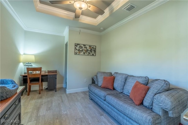 living area with light wood-style flooring, visible vents, a raised ceiling, and ornamental molding