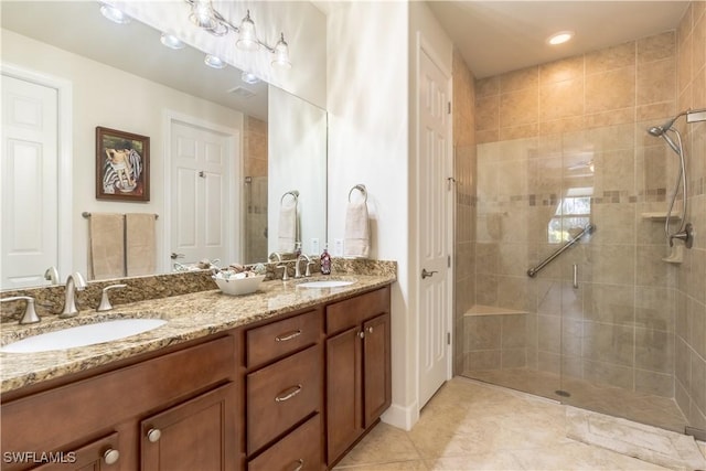 bathroom featuring double vanity, a stall shower, a sink, and tile patterned floors