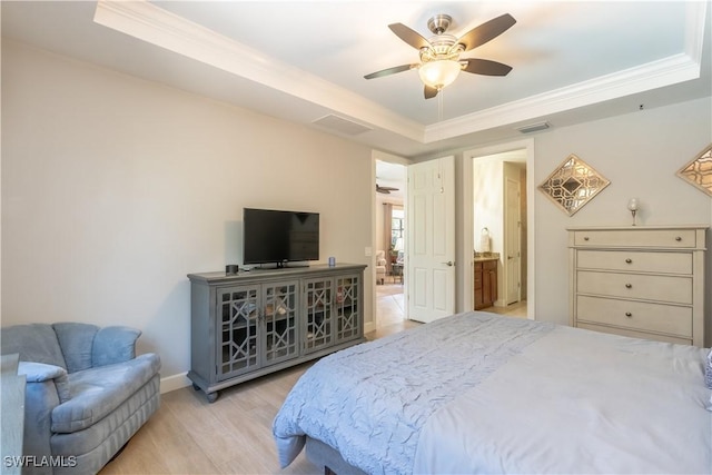 bedroom featuring connected bathroom, light wood-style flooring, visible vents, ornamental molding, and a raised ceiling