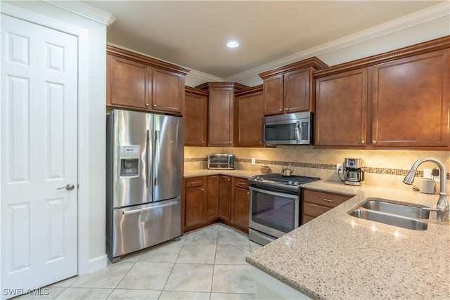 kitchen with light tile patterned floors, appliances with stainless steel finishes, light stone counters, ornamental molding, and a sink