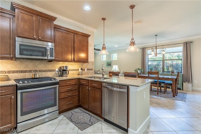 kitchen with crown molding, stainless steel appliances, hanging light fixtures, a sink, and a peninsula