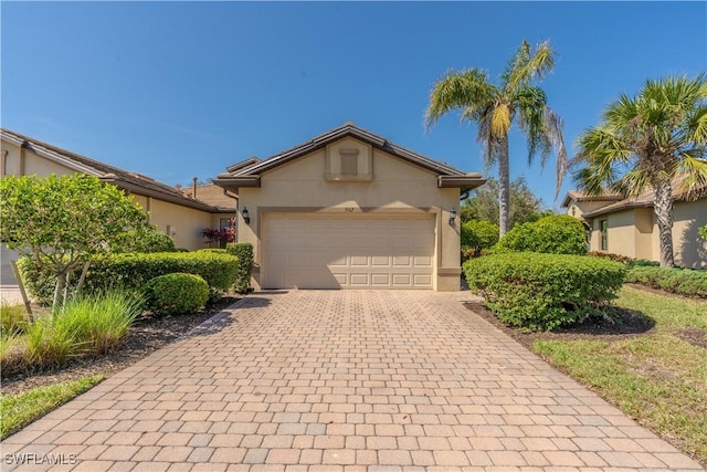 ranch-style house featuring decorative driveway, an attached garage, and stucco siding