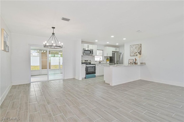 kitchen with kitchen peninsula, stainless steel appliances, tasteful backsplash, white cabinets, and pendant lighting